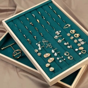 Green velvet and wood jewelry display tray showcasing gold rings and pearl earrings