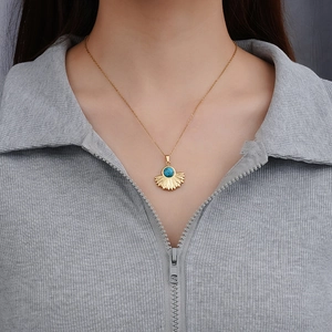 Elegant 18k gold fishtail necklace with turquoise pendant shown on a female model