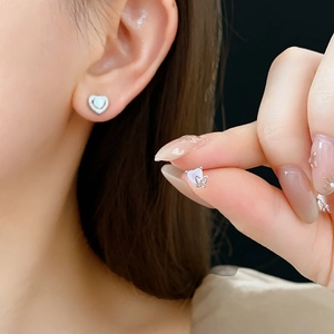 Detailed view of silver heart and butterfly stud earrings with sparkling cubic zirconia stones