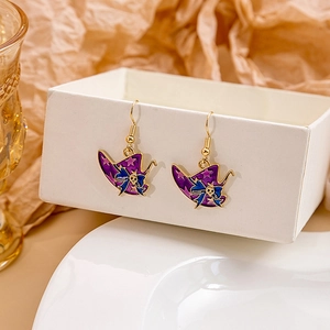 Detail of purple drop oil earrings with blue bow and skull charm for Halloween