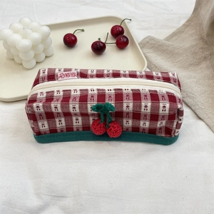 Detailed view of the red and white checkered storage bag with crochet cherry accents
