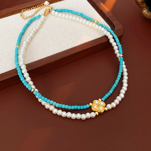 Collana a doppio strato con perle turchesi, perle bianche e ciondolo a quadrifoglio d'oro