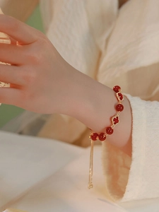 Detail view of red agate beaded bracelet with gold clover motifs and adjustable drawstring