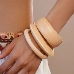 Macro shot of three assorted width wooden bangles featuring natural wood grain texture