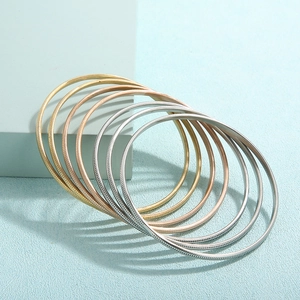 Dettaglio macro di set di bracciali testurizzati in finiture oro, oro rosa e argento
