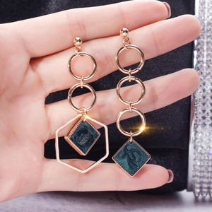 Detail of asymmetric gold geometric drop earrings with dark green glitter diamond charms