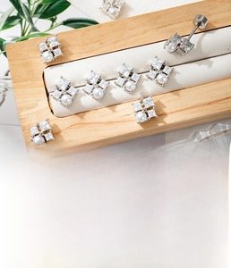 Detailed view of silver zircon geometric stud earrings with pearl on wooden stand