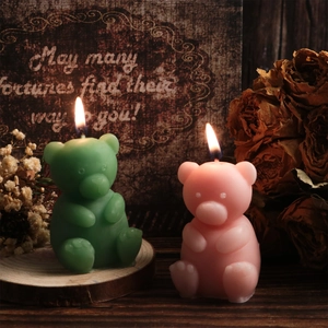 Detail view of pink and green bear scented candles on a rustic wooden tray with dried flowers