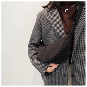 Minimalist black crescent crossbody bag shown as a functional chest bag on a model