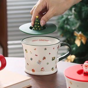 Detail of Christmas ceramic mug with green lid and Christmas tree handle in hand