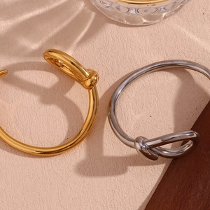 Detail of twisted knot open bangles in polished 18K gold and silver finishes