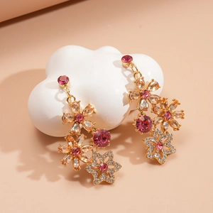 Close-up of gold-plated flower tassel earrings with pink and champagne crystals