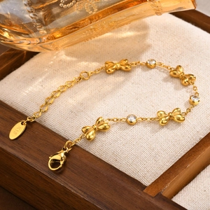Gros plan du bracelet doré avec nœuds et zircons sur fond de bois et de lin blanc