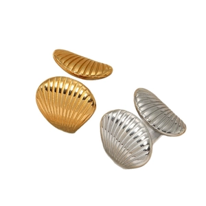 Minimalist shell jewelry set featuring golden stud earrings and silver open ring on white