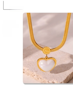 Detail shot of a vintage gold heart pearl pendant on a sleek snake chain necklace