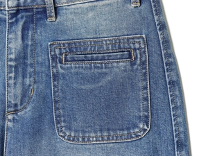 Detailed close-up of blue wash denim texture with stitching and cargo pocket design