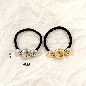 Detailed size view of metallic ball hair ties in gold and silver colors on white background