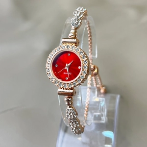Detail view of rose gold quartz watch with sparkling rhinestones and a red dial