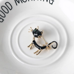 Detail of a black enamel cat brooch with green eyes and crystal rhinestones on a tray