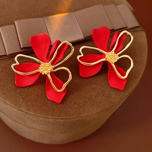 Detail of vintage flower earrings with red petals and gold hollow metal on brown velvet box