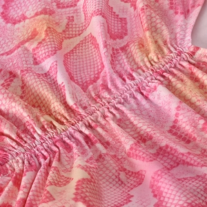Close-up of pink snake skin print fabric featuring detailed elastic smocked texture