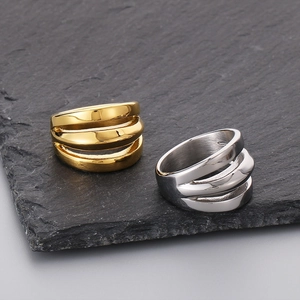 Detail view of gold and silver triple-layered stainless steel rings on a dark rock background