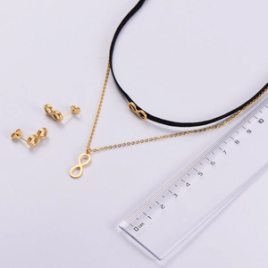 Vue détaillée de l'ensemble collier et boucles d'oreilles infini doré avec échelle