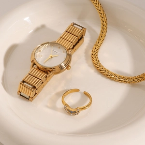 Close-up of 18k gold plated watch, sparkling crystal ring and necklace in ceramic tray