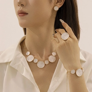 Detail view of model wearing white enamel gold necklace and matching jewelry set