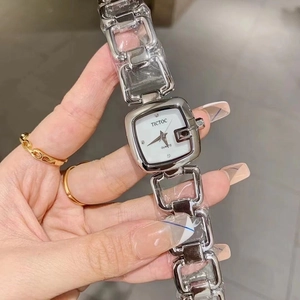Close-up of silver square quartz watch with metal chain strap worn on a female wrist