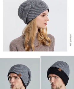 Detailed close-up of dark grey knitted beanie showing texture and leather logo patch