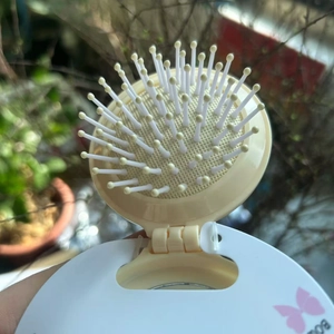Macro detail of portable folding hairbrush with pink butterfly pattern on yellow plastic