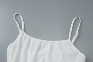 Close-up of white ribbed knit fabric texture and adjustable strap on a sexy U-neck camisole