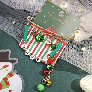Détail de broche de Noël avec perles rouges vertes, cloche festive et breloque Père Noël