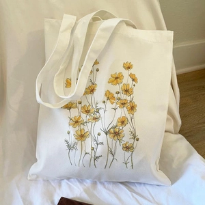 Floral aesthetic printed canvas tote bag with yellow cosmos on a cream white surface