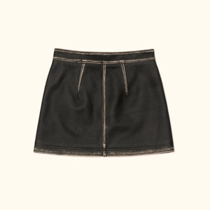Détail d'une mini-jupe en cuir noir vintage avec bords marron usés et texture de qualité
