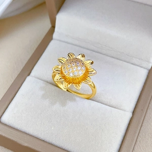 Macro shot of gold sunflower ring with pavé-set center stones in a jewelry box