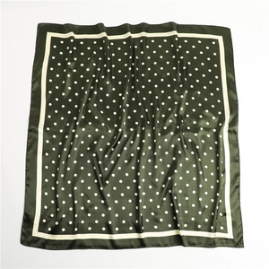 Macro detail of dark green satin scarf featuring white polka dots and elegant white border