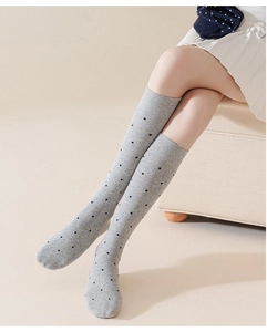 Detail of grey knee-high cotton socks with black polka dots and ribbed elastic cuffs