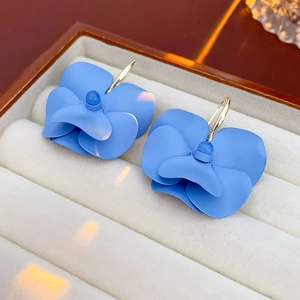 Close-up of matte sky blue 3D orchid earrings placed in a white velvet jewelry box