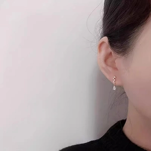Close-up of elegant gold pear-shaped drop earrings with crystals worn by a model