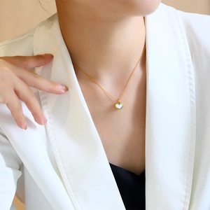 Minimalist gold titanium steel necklace with a white shell heart pendant on a model