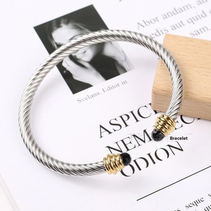 Detailed close-up of a twisted cable stainless steel bangle with gold accents and black stones