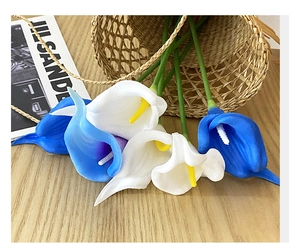 Close-up of artificial white and blue PU calla lilies on a rustic wooden table surface