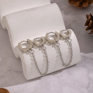 Boucles d'oreilles créoles punk en acier titane avec chaînes sur support marbré