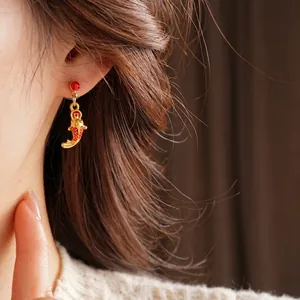 Boucles d'oreilles carpe koï élégantes en émail rouge et doré sur un mannequin
