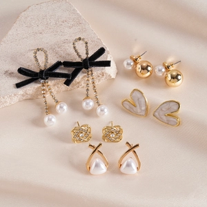 Detailliertes 5er-Set goldene Ohrringe mit Perlen, Strass und schwarzen Schleifen auf Seide