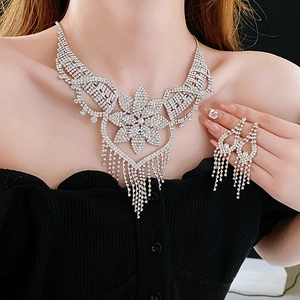 Close-up of sparkling silver floral necklace and tassel earrings set on a model