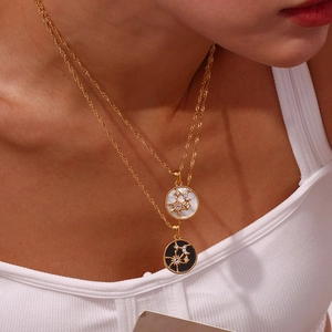 Detail of layered gold sun and moon pendants with mother of pearl and black enamel