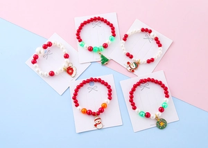 Detail of five Christmas beaded bracelets with festive charms on white display card